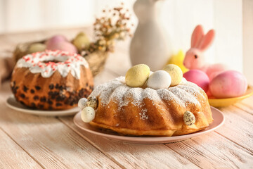 Plate with tasty Easter cake and painted eggs on white wooden table