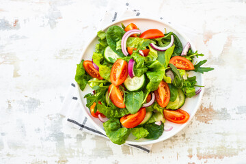 Fresh green salad with leaves and vegetables. Arugula, spinach, tomatoes and onion.
