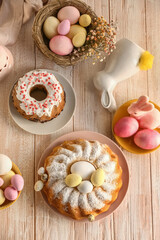 Composition with tasty Easter cakes, painted eggs and bunnies on white wooden background