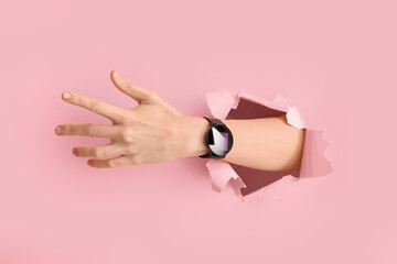 Female hand and smartwatch visible through torn pink paper