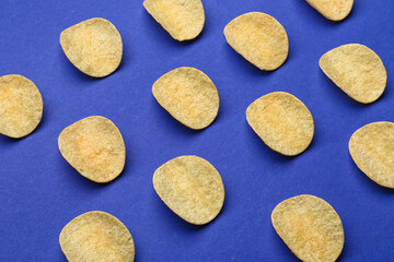 Many delicious potato chips on blue background