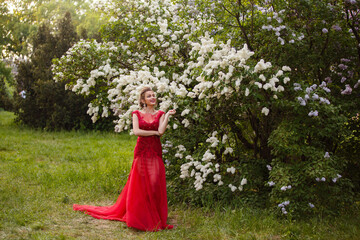 Beautiful woman in blooming lilac garden. Half-body Portrait in sunset light. Pretty young caucasian girl in beauty princess character. Romantic spring mood. Spring dreamy lady. Make up and hairstyle