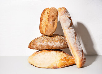 Loaves of different bread on table white wall