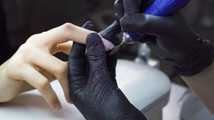 Electric nail file. Nail extensions at beautician