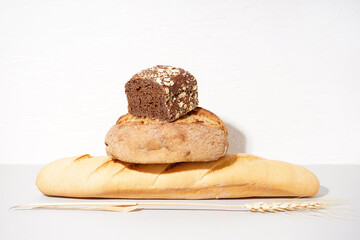 Stack of different bread loaves on table near white wall