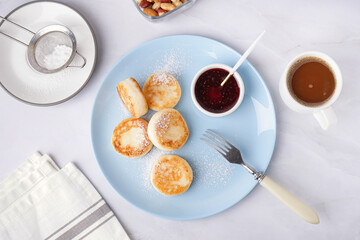 Plate with tasty cottage cheese pancakes, strawberry jam and cup of coffee on light background