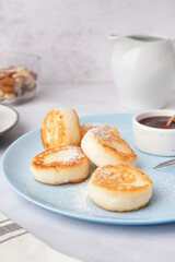 Plate with tasty cottage cheese pancakes and strawberry jam on light background, closeup