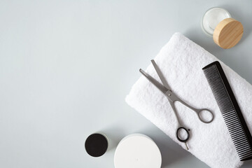 Hairbrush, filleting scissor and jars of creams are on a grey background. View from the top point....