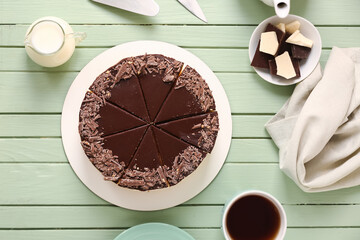 Tasty birds milk cake, cup of coffee and chocolate on color wooden background