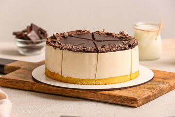 Wooden board with tasty birds milk cake on light table, closeup