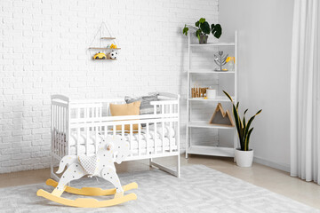 Interior of children's bedroom with crib, rocking horse and shelving unit
