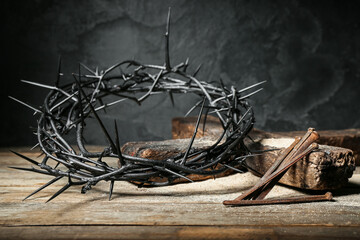 Crown of thorns, nails and cross on wooden table