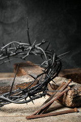 Fototapeta na wymiar Crown of thorns, nails and cross on wooden table, closeup
