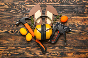 Construction tools with paper bunny ears, Easter eggs and eucalyptus on dark wooden background