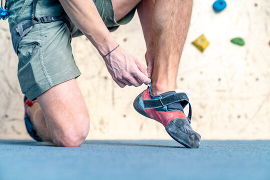 putting on climbing shoes next to the climbing wall
