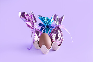 Holder with chocolate Easter eggs on color background