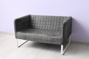 Stylish grey sofa near lilac wall