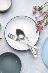 Composition with clean dishes, cutlery and floral decor on grey grunge background