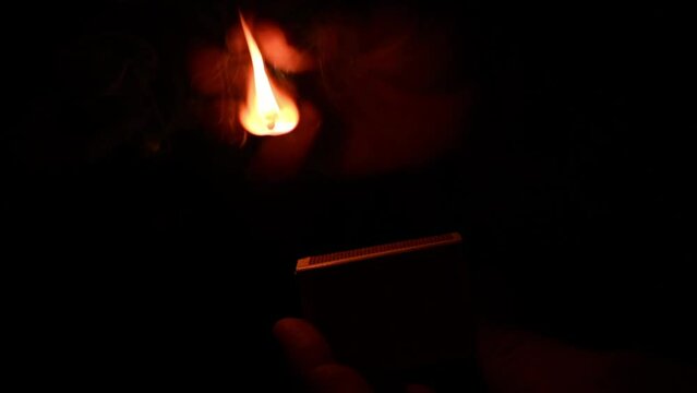Slow motion shot of a match being struck against a dark background.