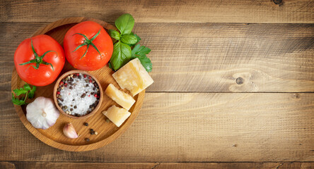 Tomatoes, parmesan cheese and spices on wooden background. Italian food concept, copy space.