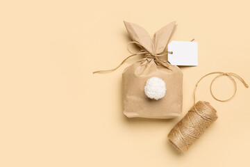 Fototapeta na wymiar Easter bunny gift bag and thread on beige background