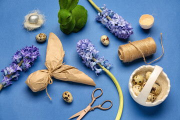 Composition with hyacinth flowers, Easter eggs, bunny and thread on blue background