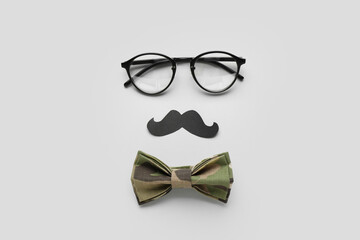 Composition with eyeglasses, paper mustache and bow tie on white background