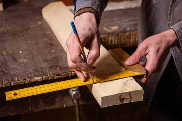A carpenter works in a workshop with a saw, planer and various tools