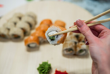 Woman holding sushi in hand with chopsticks