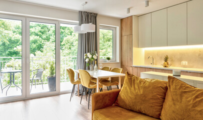 living room interior with modern yellow sofa, dining room with stylish chairs and kitchen furniture. New design in room in apartment with white wall.	