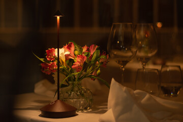 Romantic restaurant table setting dinner close-up, with roses, warm light