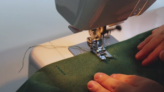 Close-up sewing proccess sewing machine. Side view needle work. Handmade, making handcrafted green velveteen fabric, hand-sewn dress. Top view creating buttonholes for buttons.  manufacturing business