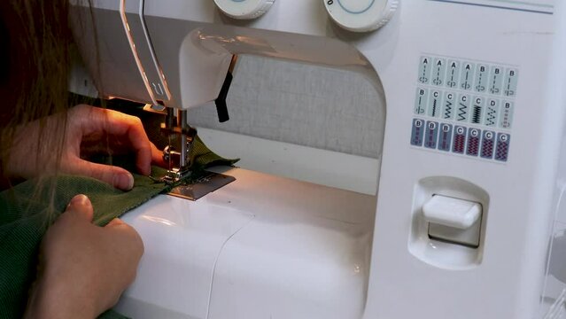 Close-up sewing proccess on sewing machine. Side view needle work. Handmade cloth, making handcrafted from green velveteen fabric, hand-sewn dress. clothing manufacturing business