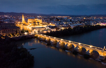 Night aerial view of Historic centre of Cordoba with antique Roman Bridge over Guadalquivir river 