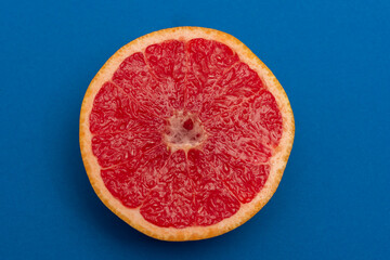 Sliced side of a grapefruit with red pulp isolated on a blue background