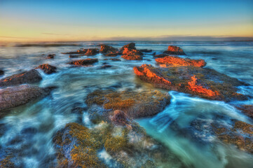 Fototapeta na wymiar Water flowing over rocks at sunset or sunrise