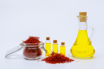 Dried saffron threads in glass bottle and oil extract on white background. A drink made from...