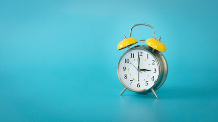 Retro silver alarm clock.  3:00, am, pm. Blue background.