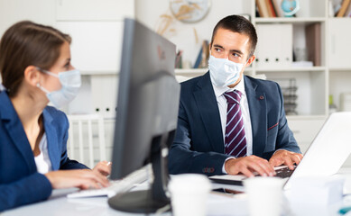 Fototapeta na wymiar Manager in protective medical mask gives task to assistant at office