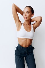 Fototapeta na wymiar A woman poses on a white wall background in pants and T-shirt and smiles beautifully at home. Healthy and beautiful facial and body skin