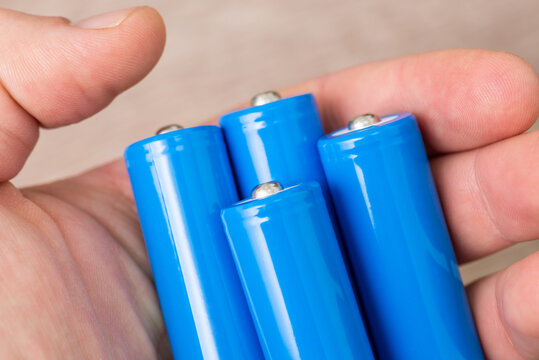 Man with 4 blue accumulators in his hand. Using 18650 type rechargeable batteries concept