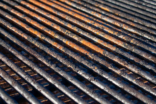 Close up photo of a rusty park grill with dirty grates