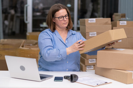 woman entrepreneur of SME work from home or depo with laptop to manage commercial operations online marketing, packaging orders, and managing online sales. e-commerce business.