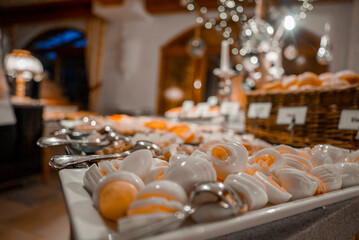 Closeup of white and yellow desserts arranged in trays at counter inside luxury alpine hotel during...