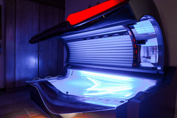 Empty modern illuminated tanning bed by wall in room of luxury hotel