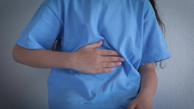 Teen feel stomach ache indoor. A child with abdominal pain suffering in the room. A concept of periods spasm and health problems indoor.
