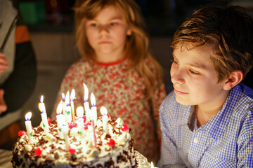 Happy preteen boy celebrating birthday. Preschool sister child and two kids boys brothers blowing together candles on cake. Happy healthy family portrait with three children siblings