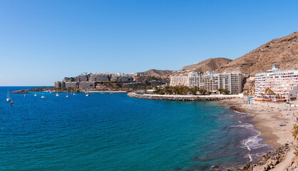 Beautiful seascape with sailboats on water surface and buildings with mountain along the seashore at Gran Canaria, Spain