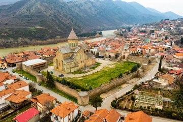 Foto op Canvas Picturesque aerial view of old Georgian city of Mtskheta surrounded by Caucasus mountains overlooking Orthodox Svetitskhoveli Cathedral in springtime © JackF