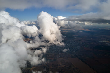 Aerial view at high altitude of earth covered with puffy cumulus clouds forming before rainstorm